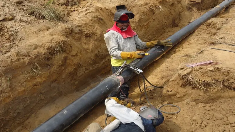 Welder repairing a leak point on buried pipeline within an excavated right of way